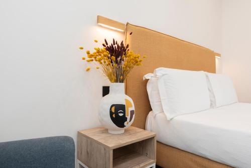 a vase sitting on a table next to a bed at NG Guest House il Gallura in Olbia