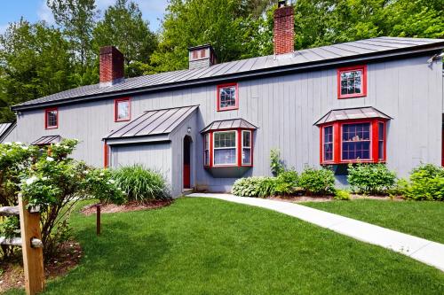 a white house with red windows and a yard at Quechee Hollow 2C in Quechee