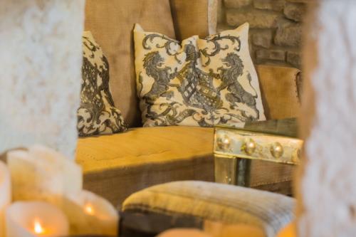 a couch with pillows and a table with candles at La Maison du Passage - Chambres - Suites premium, Spa, Piscine et Restaurant in Martignargues