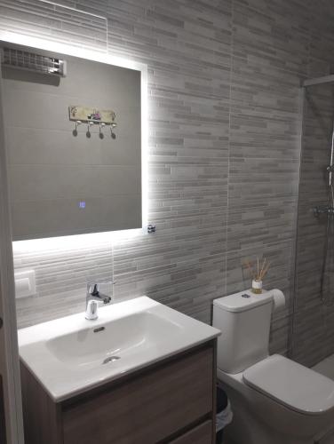 a bathroom with a sink and a toilet and a mirror at Castralvo Suites in Teruel