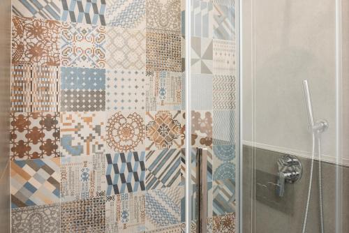 a shower with a glass door with tiles on the wall at NG Guest House il Gallura in Olbia
