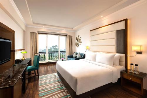 a hotel room with a large bed and a television at Radisson Jaipur City Center in Jaipur
