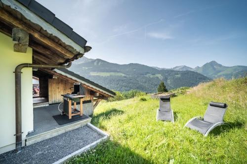 a house with two chairs and a table in the grass at Le Perray Alpine Lodge in Abondance