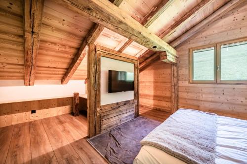 a bedroom in a log cabin with a bed and a tv at Le Perray Alpine Lodge in Abondance