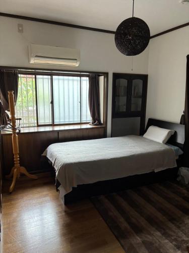 a bedroom with a large bed and a window at Guesthouse Sakichi in Beppu