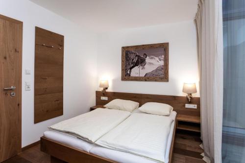 a bed in a bedroom with a picture on the wall at Residenz Wildkogelbahnen Top 4 in Neukirchen am Großvenediger