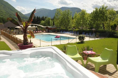 un bain à remous sur une terrasse avec des chaises et une piscine dans l'établissement Camping L'imprévu, à Vaulnaveys-le-Bas