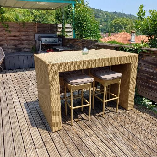 une table en osier et des tabourets sur une terrasse dans l'établissement L'ermitage, à Agen