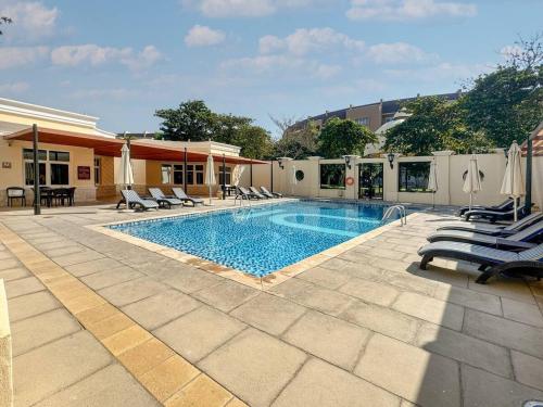a swimming pool with chaises and chairs next to a building at Air Homes - Stylish Urban Living in a Modern 1BR in Dubai