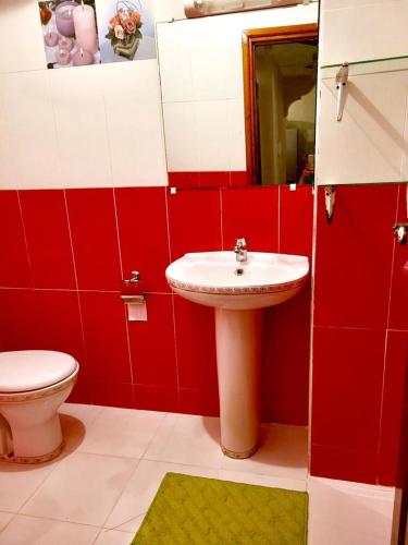 a red and white bathroom with a sink and a toilet at Family apartment close to the Beach in jadida in El Jadida