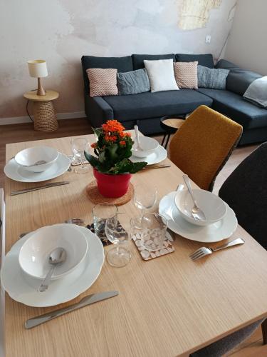 - une table à manger avec des assiettes et de l'argenterie dans l'établissement Appartement Hestia F1 bis + terrasse hyper centre, à Lons-le-Saunier