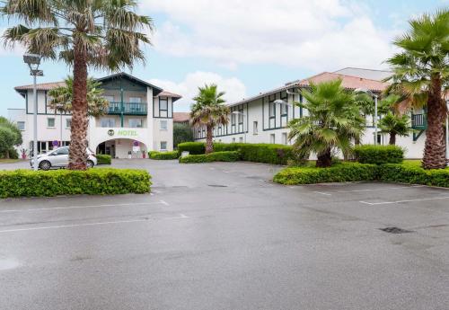 a parking lot in front of a building with palm trees at B&B HOTEL Saint Jean de Luz in Saint-Jean-de-Luz