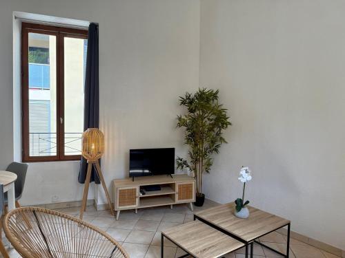 un salon avec une télévision, une table et des chaises dans l'établissement Le Duplex des Arènes,idéalement situé et lumineux, à Nîmes