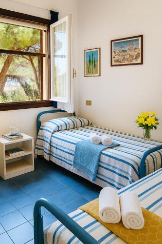 a bedroom with two beds and a window at Casa a Calaverde pochi passi dal mare terrazza aria condizionata WiFi e parcheggio in Forte Village