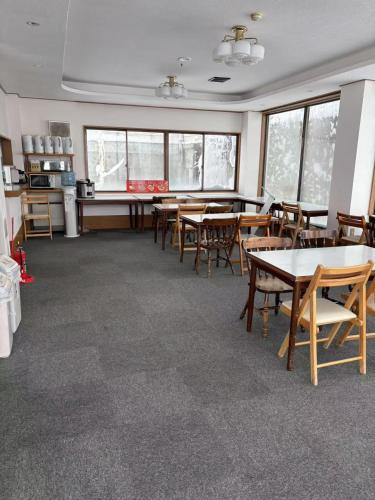 a dining room with tables and chairs and windows at Yuzawa YUKITORA 雪虎 in Minami Uonuma
