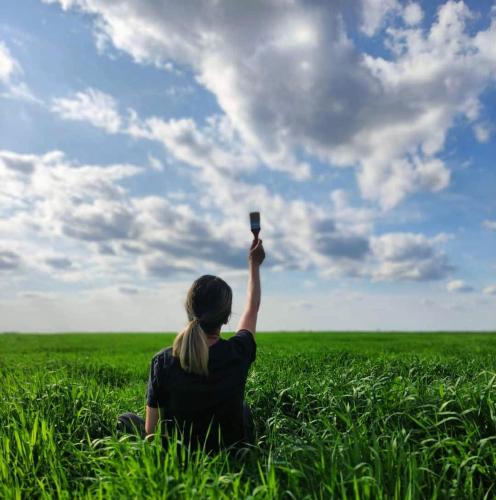 a woman holding up a cell phone in a field at La Colibe, cătun arhaic ecologic in Constanţa