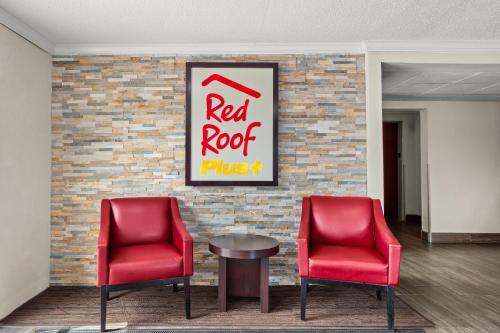 two red chairs and a table in front of a brick wall at Red Roof PLUS Belleville in Belleville
