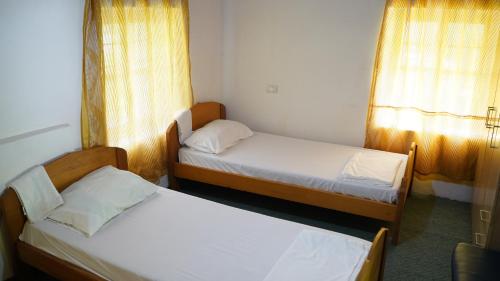 a room with two beds and two windows at Motina River Guesthouse in Tropojë