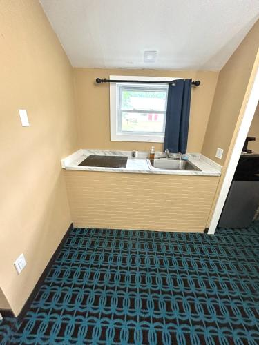 a small bathroom with a sink and a window at The Villager Motel in Bartlett