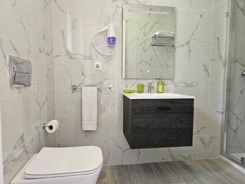 a white bathroom with a toilet and a sink at Curtido House in Aveiro