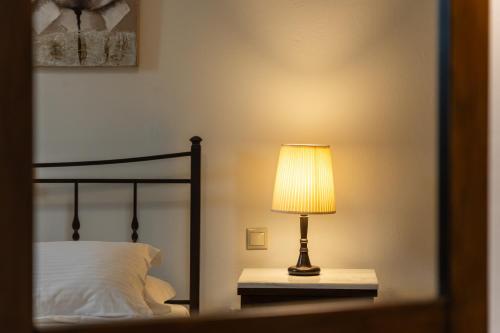 a lamp sitting on a table next to a bed at Ostria Hotel  in Adamas