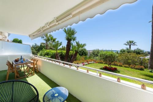 un balcon avec une table, des chaises et des palmiers dans l'établissement Cannes Garden-Level 1-Br Apartment Sea View, à Cannes