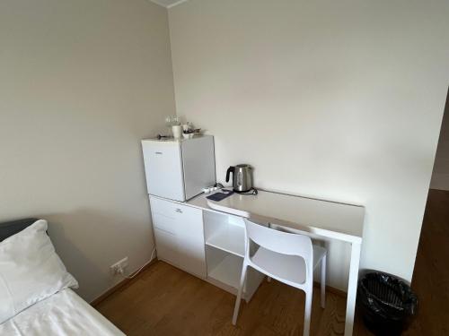 a small white kitchen with a refrigerator and two chairs at Aisa Street apartments in Pärnu