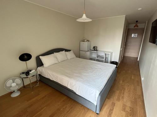 a bedroom with a white bed and a refrigerator at Aisa Street apartments in Pärnu