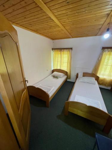 a bedroom with two beds and a wooden ceiling at Motina River Guesthouse in Tropojë