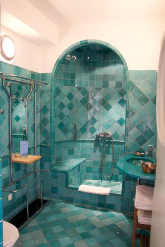 a blue tiled bathroom with a shower and a sink at La Ferme Rose-Hôtel de Charme in Moustiers-Sainte-Marie