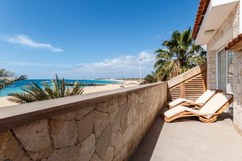 two lounge chairs on a balcony overlooking the beach at Villa ao Mar in Santa Maria