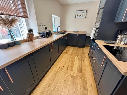 a kitchen with blue cabinets and a wooden floor at The Hebridean - Rooms & Apartments in Broadford