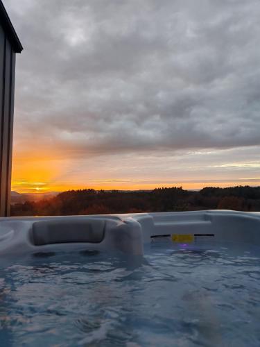 un bain à remous avec un coucher de soleil en arrière-plan dans l'établissement Chalet moderne entre Evasion Design et Nature, à Ruynes-en-Margeride