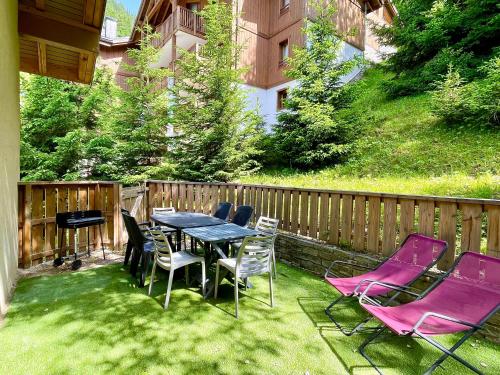 a patio with a table and chairs on the grass at Club Alpina - Champagny-en-Vanoise in Champagny-en-Vanoise