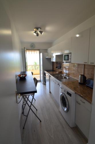 une cuisine avec une table et une machine à laver dans l'établissement PLEIN CIEL - Appartement 5 personnes avec piscine sur la Corniche Fleurie à Nice, à Nice