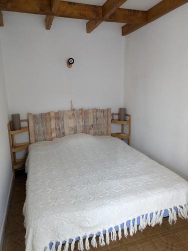 - un lit blanc dans une chambre dotée de plafonds en bois dans l'établissement Maison au bord de l'océan, à Vaux-sur-Mer