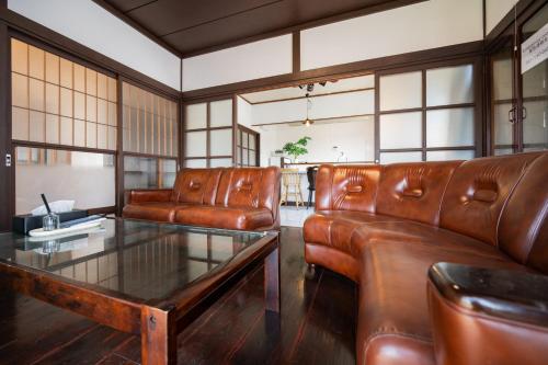 a living room with leather couches and a glass table at ひとふく塩釜 in Shiogama