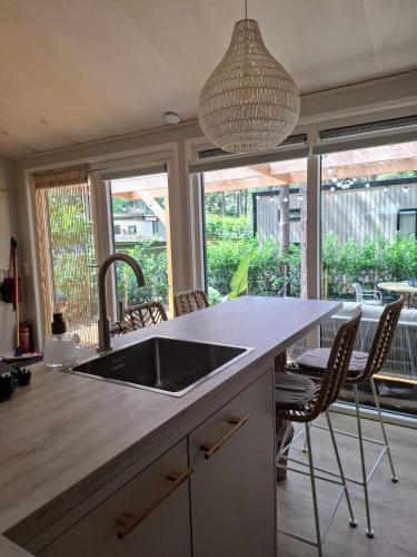 a kitchen with a sink and a counter with chairs at Thuisje van Hout, tiny house in Drentse natuur in Zuidwolde