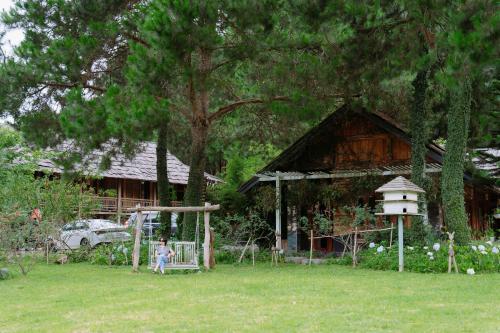 a child standing in a yard in front of a house at The Nordic Village - Evergreen Retreat in Mộc Châu