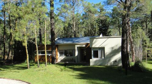 a small white house in the woods at Guindo Cariló in Carilo