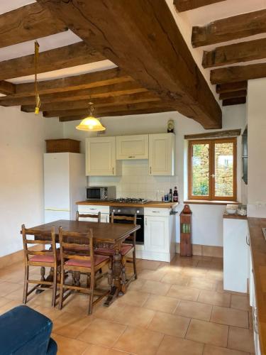 une cuisine avec une table et des chaises dans une pièce dans l'établissement Le Refuge de Montbroux, 