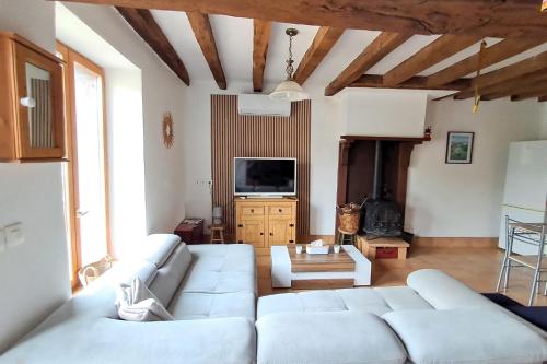 - un salon avec des canapés blancs et une télévision dans l'établissement Le Refuge de Montbroux, 