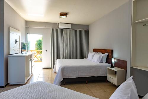 a hotel room with two beds and a balcony at Resort Pedra do Sonho in Janaúba