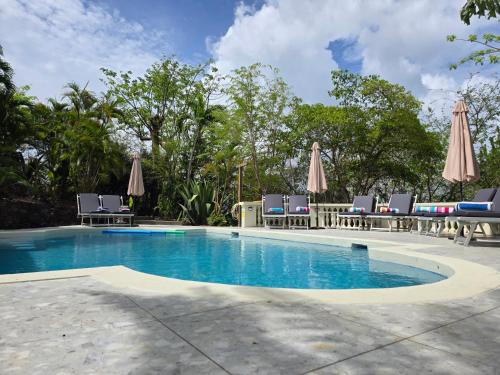 una piscina con sedie e ombrelloni di Large Beautiful Villa with Ocean Views and private pool - 3 Bedroom Listing a Cap Estate
