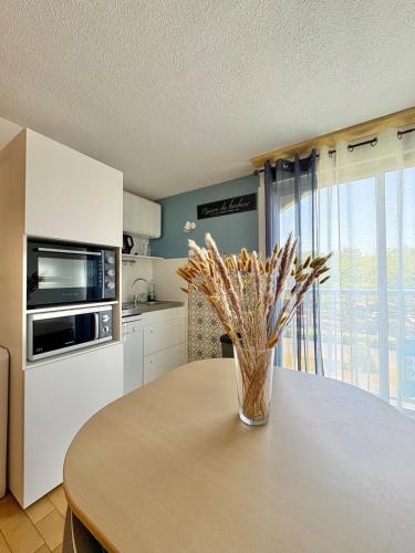 une cuisine avec une table avec un vase de fleurs dessus dans l'établissement Sunny Break Appartement près des plages, au Cap d'Agde