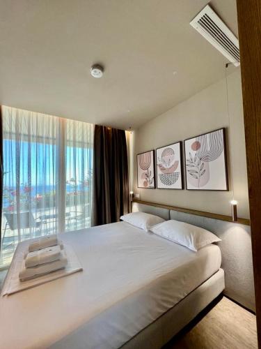a bedroom with a large bed and a large window at Green Condo Hotel Palase in Palasë