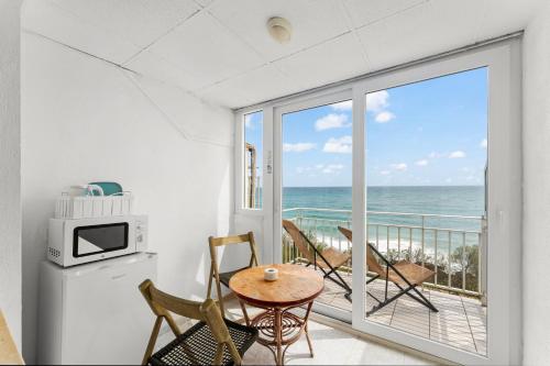 a room with a table and chairs and a balcony with the ocean at Amena Mar Hotel in Sa Coma