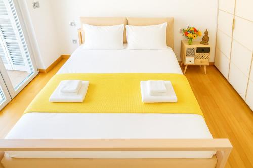 a bedroom with a large bed with yellow and white sheets at Zen Garden House - in front of the metro in Pero