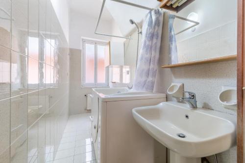 a white bathroom with a sink and a shower at Hostdomus-Finalmarina apartment in Finale Ligure