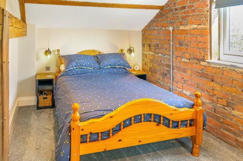 a wooden bed in a room with a brick wall at Luxury Escape with Cinema, Pool Table & Darts in Leeds